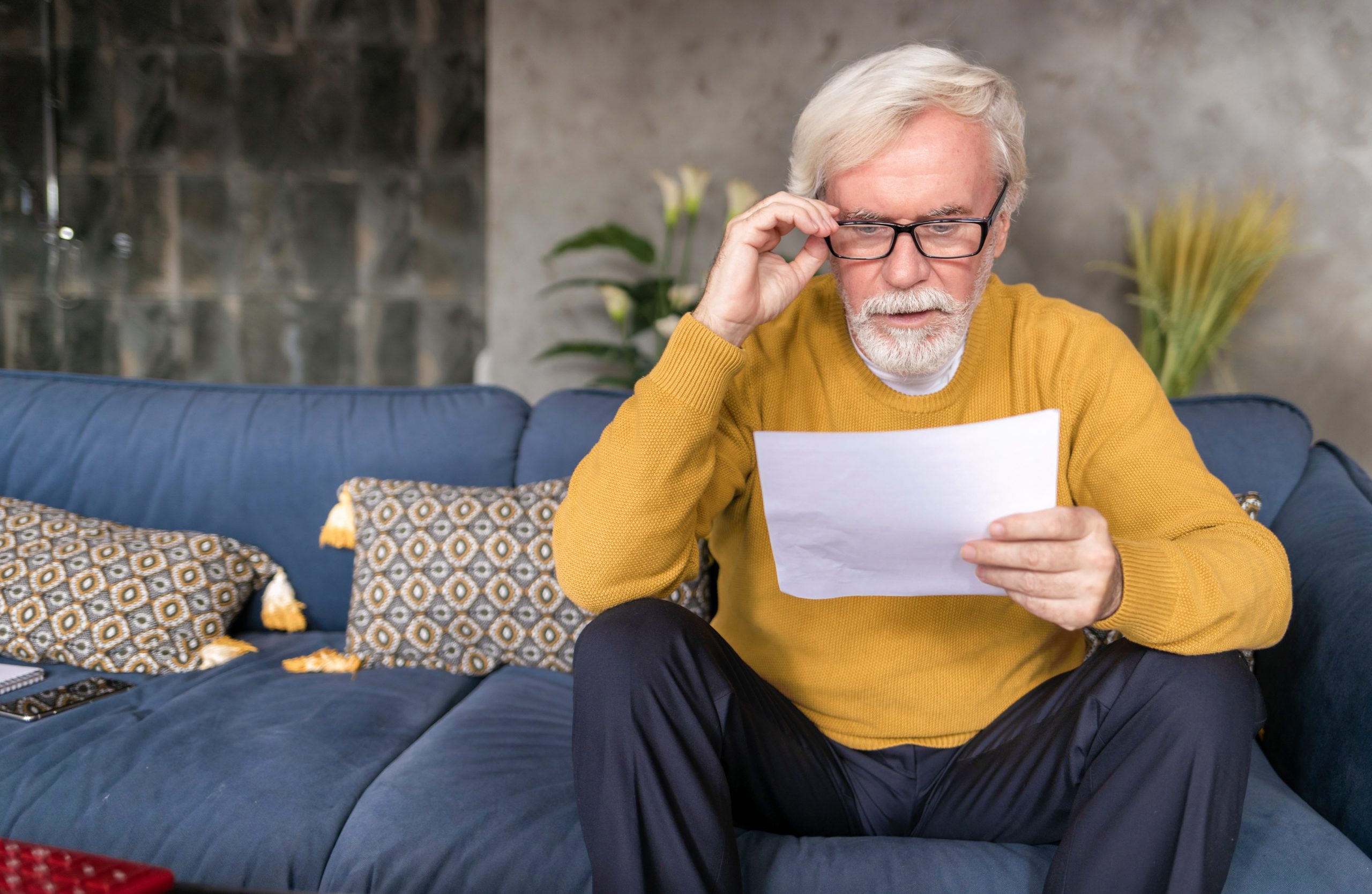 Adult man reading letter with confused face from social service.