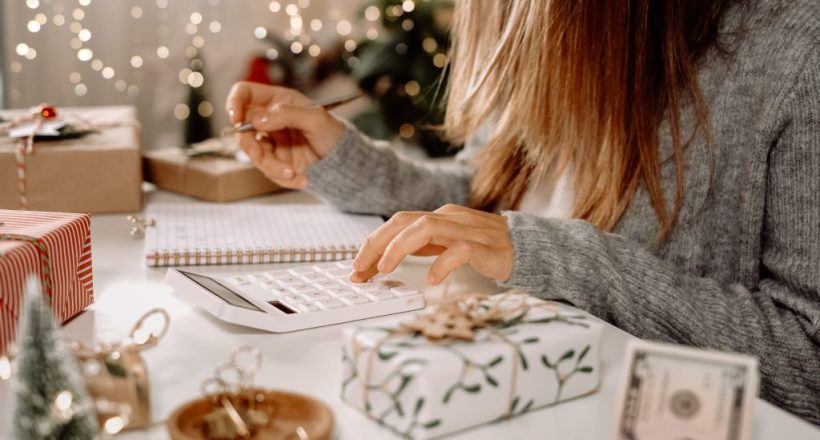 Girl counting US Dollar bills, using calculator, and writing expenses. Woman doing budget, estimating money balance for shopping spree. Female accountant paying taxes. Girl counting Christmas gifts