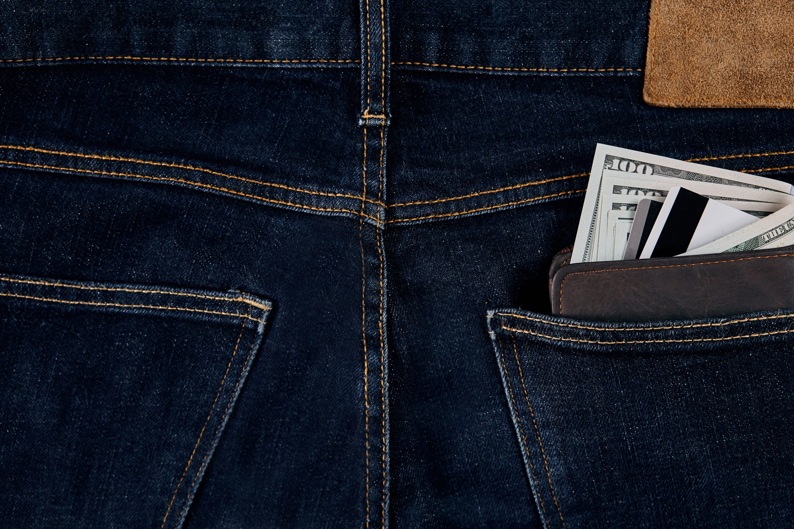 Money, Debit card and Credit card are in pocket of blue jean on wooden background with copy space.