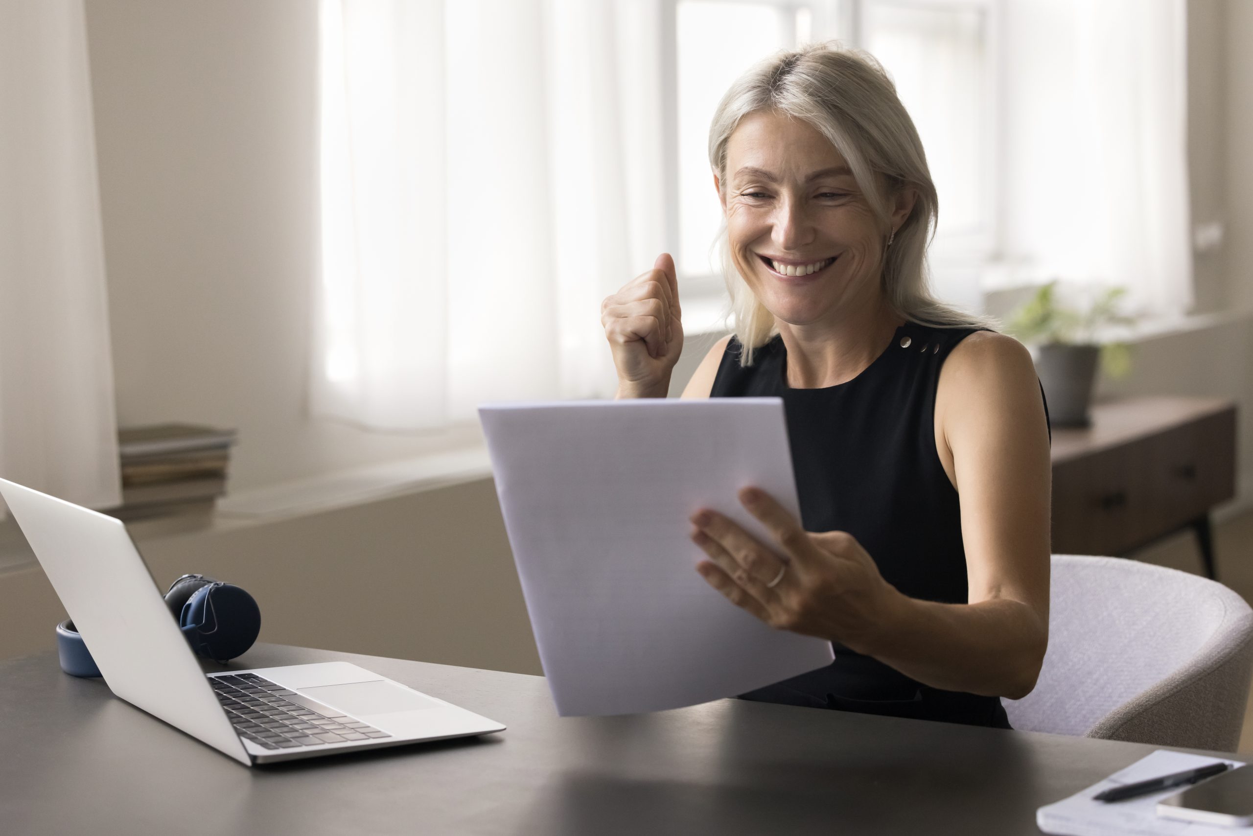 Older woman sit at table read documents feel happy