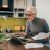 Portrait of a senior woman working with laptop and documents in the kitchen.