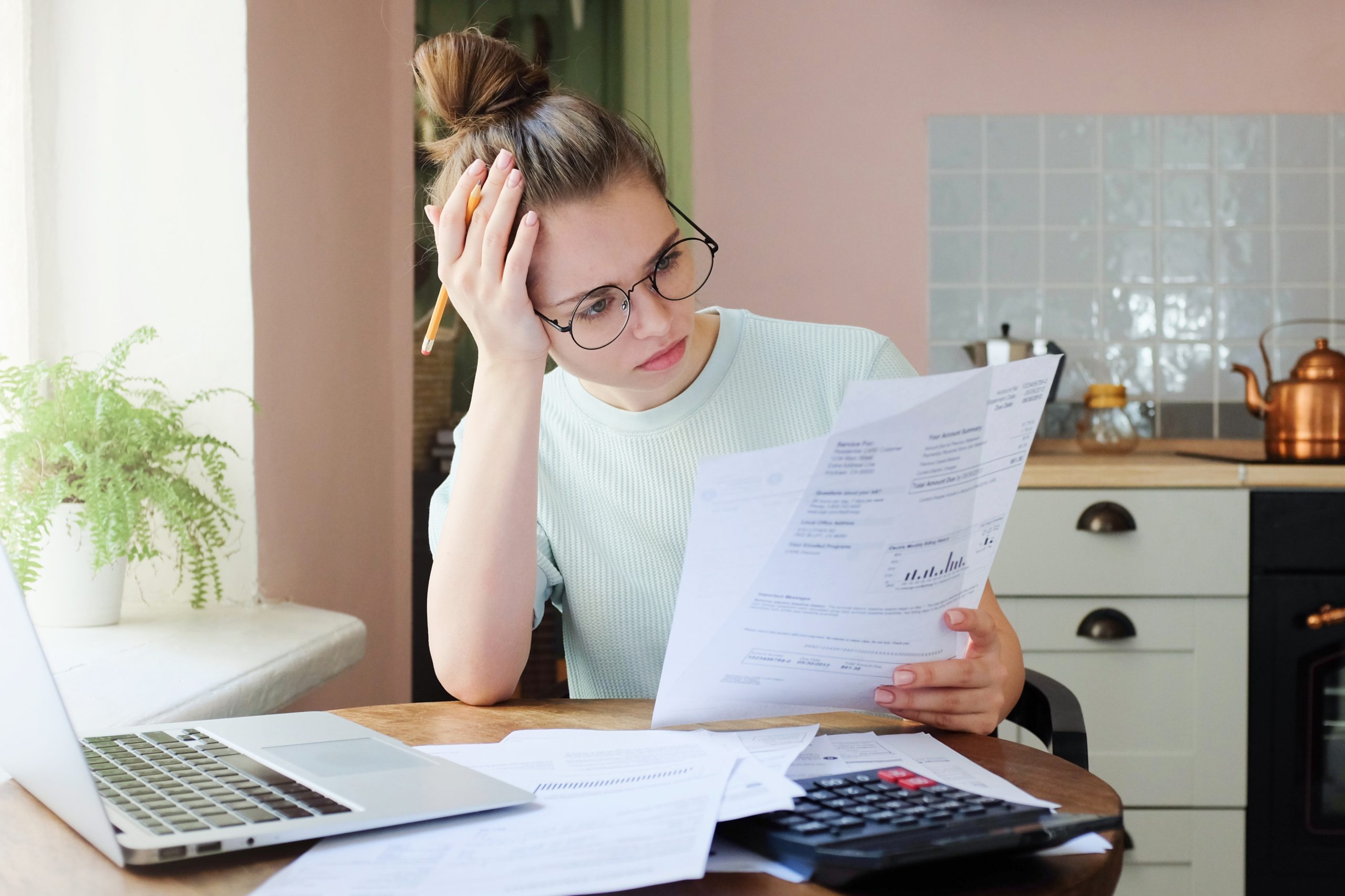 Indoor shot of young European Caucasian girl looking at financial documents at home with deeply bored face looking sick and tired of her economic problems, trying to check counts and all details Indoor shot of young European Caucasian girl looking at financial documents at home with deeply bored face looking sick and tired of her economic problems, trying to check counts and all details